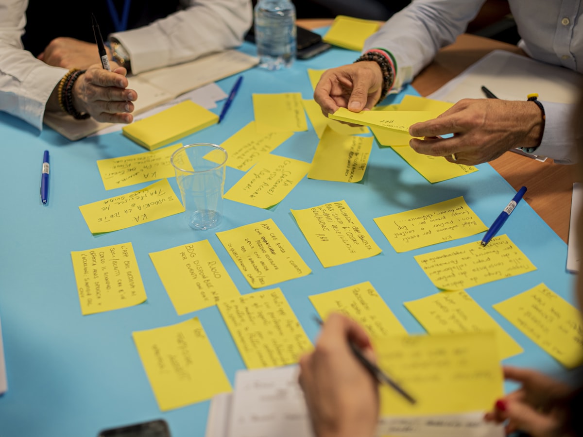 Hands arranging handwritten sticky notes across a workshop table