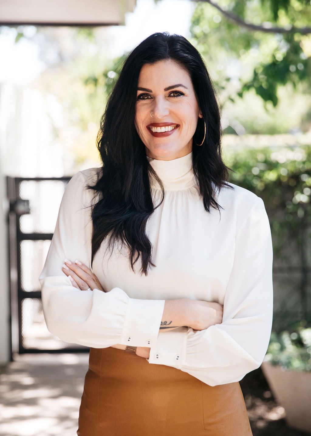 Dr. Shaleen Kendrick smiling with arms crossed in a sunlit courtyard